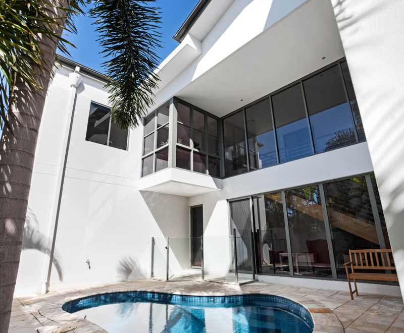 A small swimming pool near palm tree next to a modern house